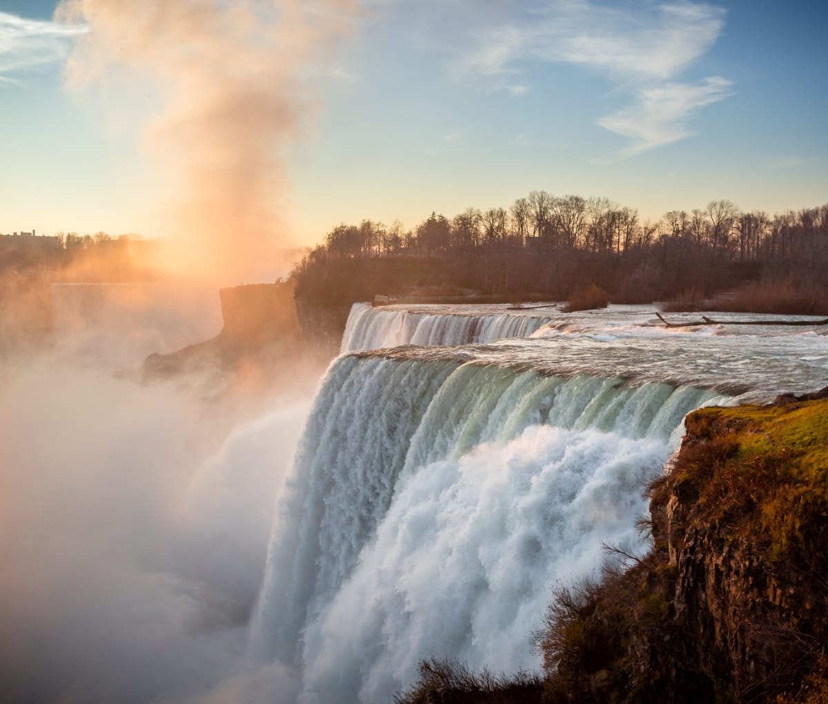 Niagara falls waterfall at sunset, there is a bare wooded forest surrounding it.